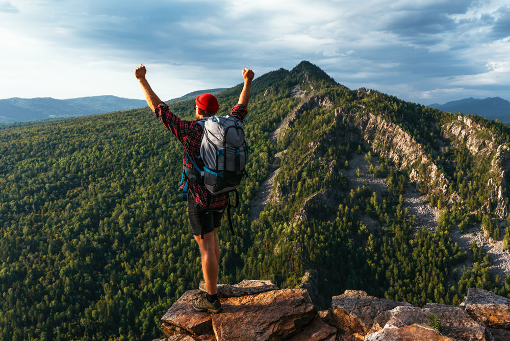 hombre celebrando cima montaña
